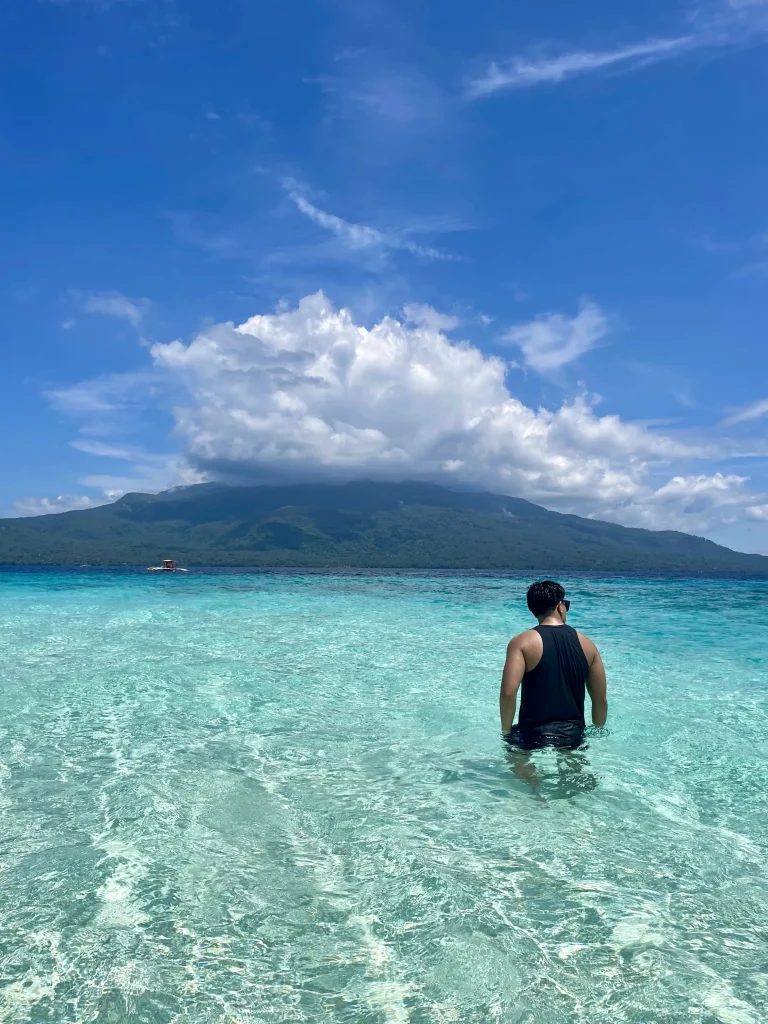 Man posing his back in Mantigue Island with Mount Hibok-Hibok in the background
