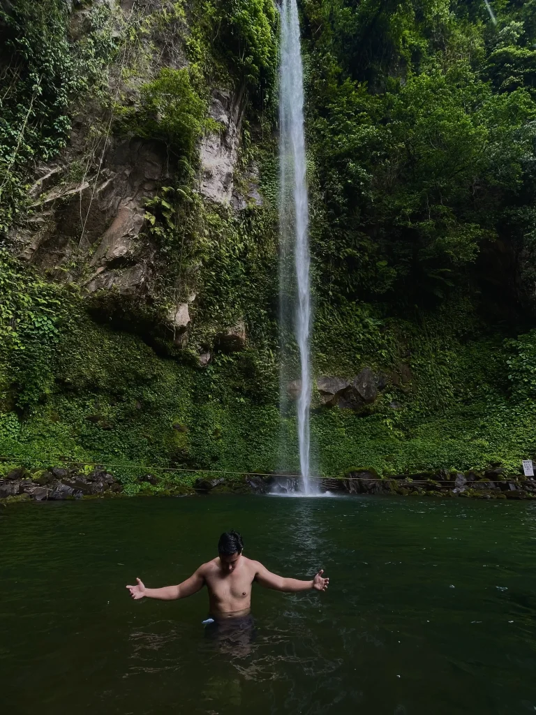 Man posing with hands open wide in the Katibawasan Falls Camiguin