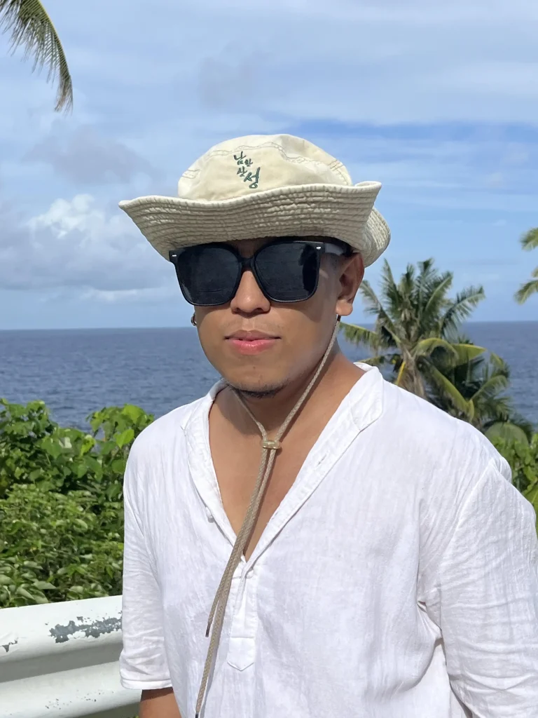 Man wearing a white shirt and a fisherman's hat with glasses posing on Siargao island