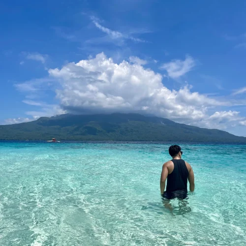 Man posing his back in Mantigue Island with Mount Hibok-Hibok in the background